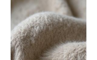 Nærstudie av teksturert, myk norsk ull i en naturlig gråhvit farge.